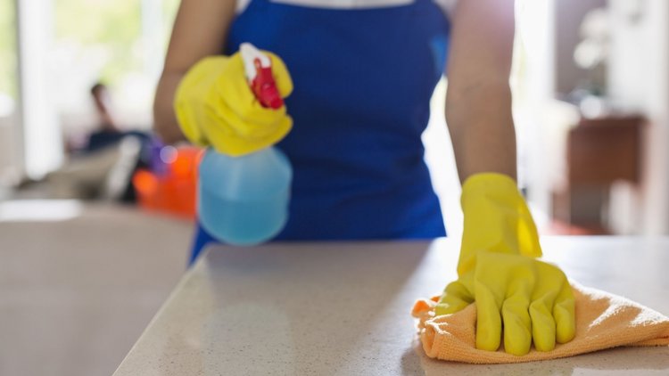 Professional house cleaner sanitizing a countertop.